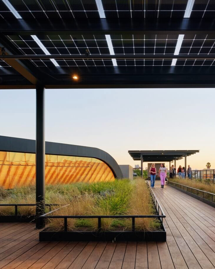 Solar panel pergola on a modern rooftop walkway with greenery at sunset