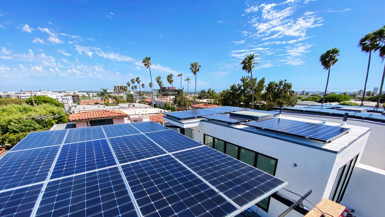 Rooftop solar panels on a modern home with palm trees and a bright blue sky