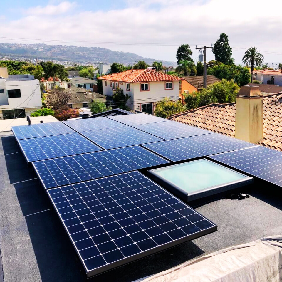 Rooftop solar panel system on a home with a skylight, overlooking a suburban hillside