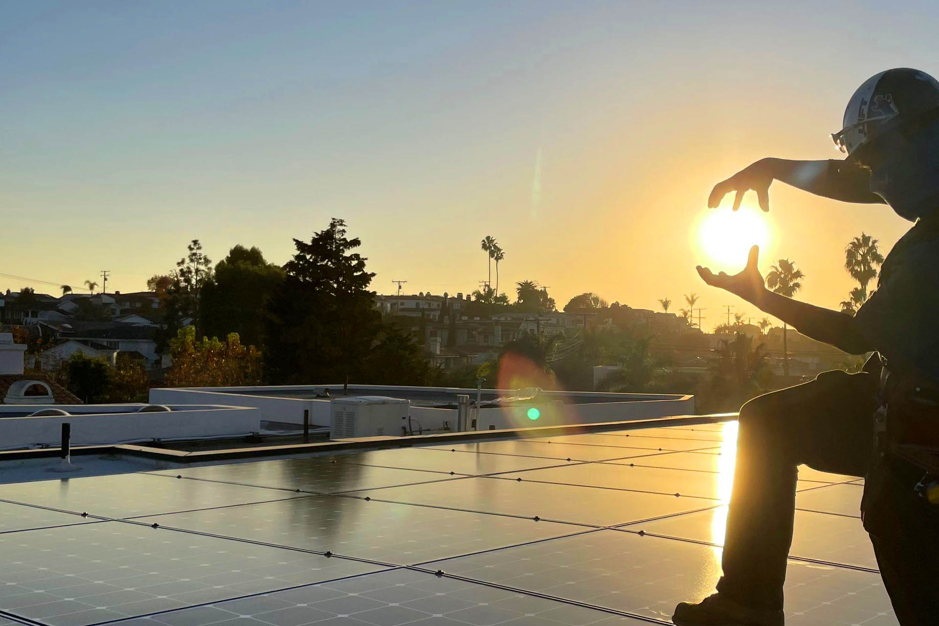 Solar technician playfully framing the sun over rooftop solar panels by Xero