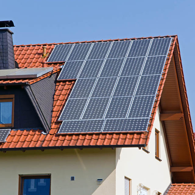 Residential home with rooftop solar panels installed on a red tile roof