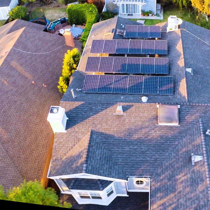 Aerial view of a residential home with rooftop solar panels installed on a shingled roof