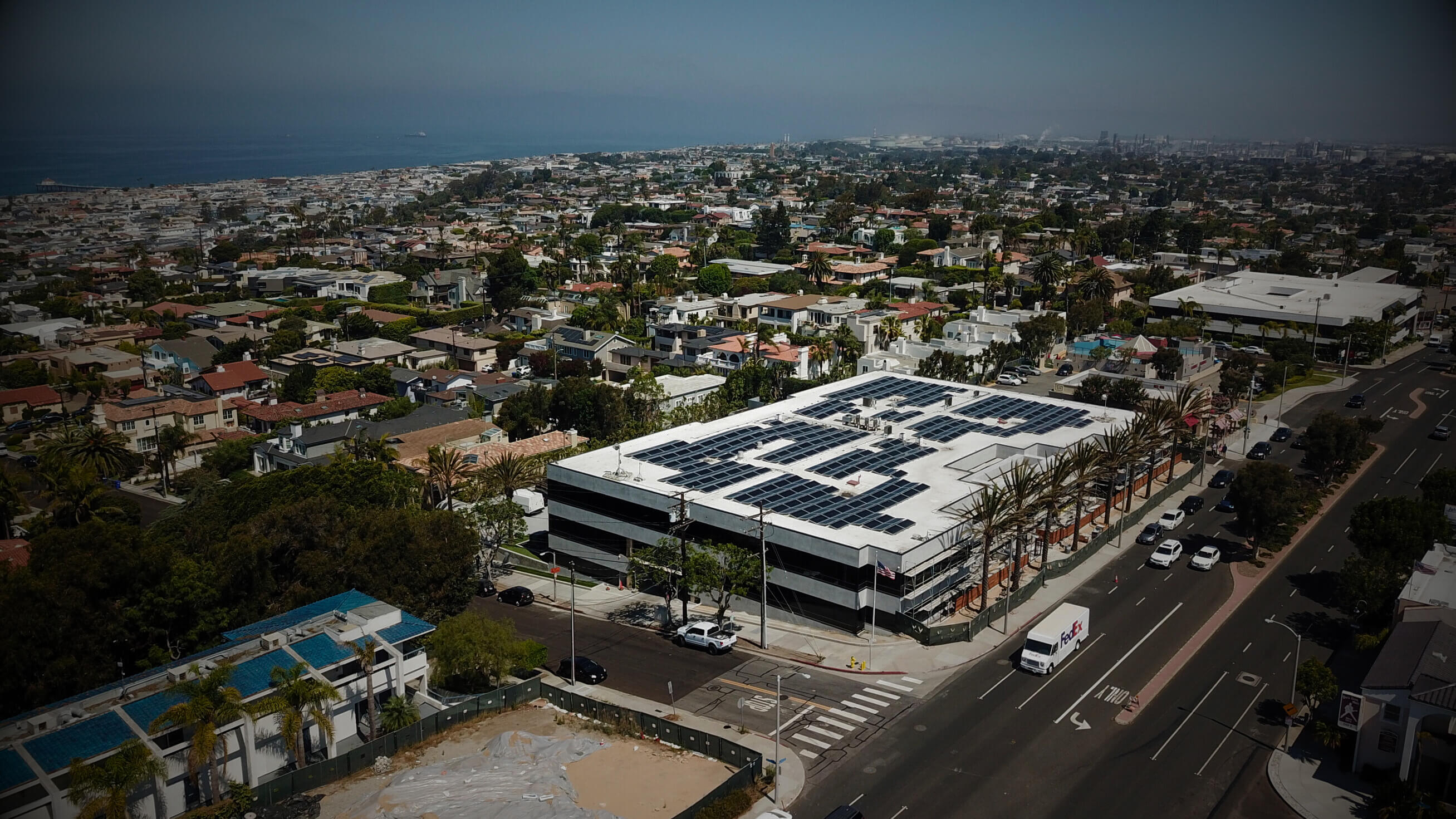 Aerial view of a commercial building with rooftop solar panels in a coastal city