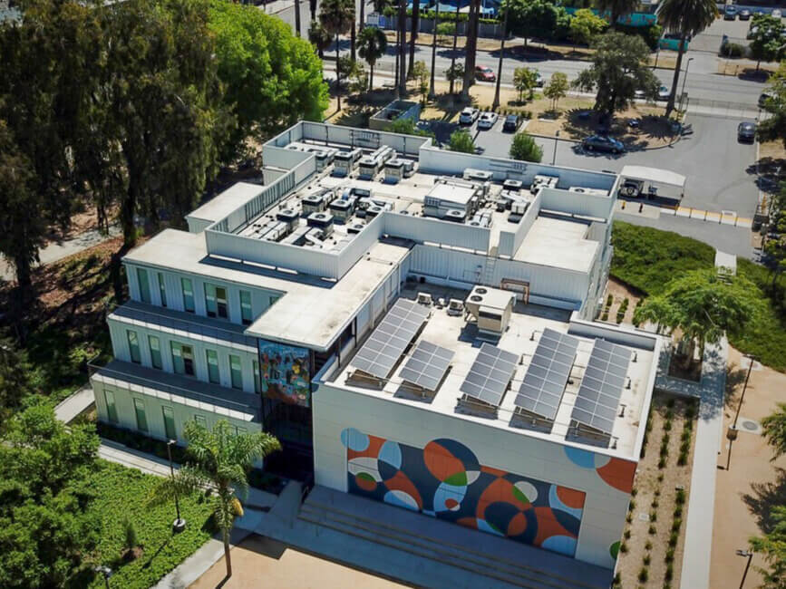 Aerial view of a modern building with rooftop solar panels and colorful mural