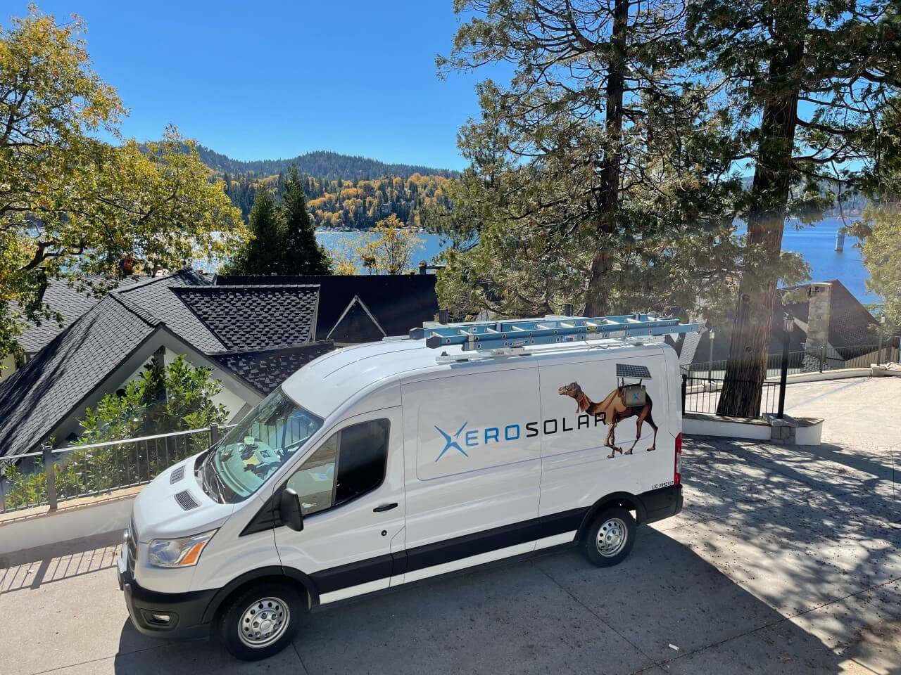 Xero Solar service van parked near a scenic residential area with a lake view